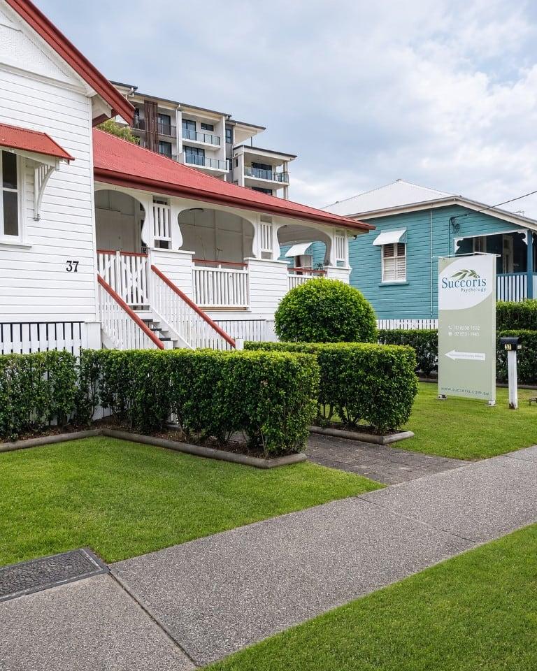 Succoris Tweed Heads, a white weatherboard house with a red roof and the Succoris sign out front
